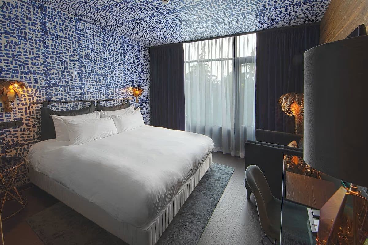 Kamerhoge vitrages achter het bed in het Apollo Hotel